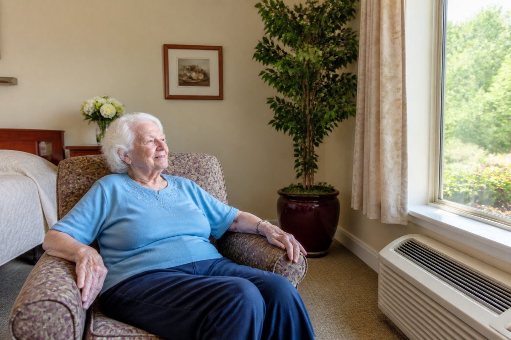 Close-up of a nursing home resident in a clean, bright room with well-maintained carpet and fresh indoor air quality, natural light streaming through windows, peaceful expression