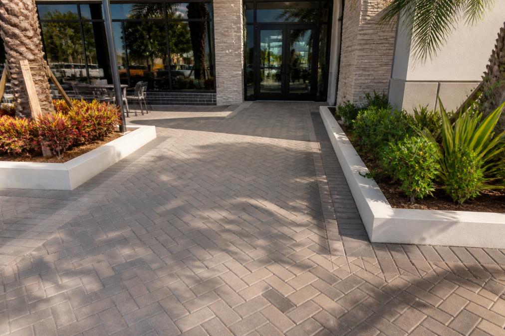 Commercial Hardscape Design for Retail: 2026 Guide 2 Herringbone concrete pavers at a retail plaza entrance featuring durable hardscape design for high-traffic areas.