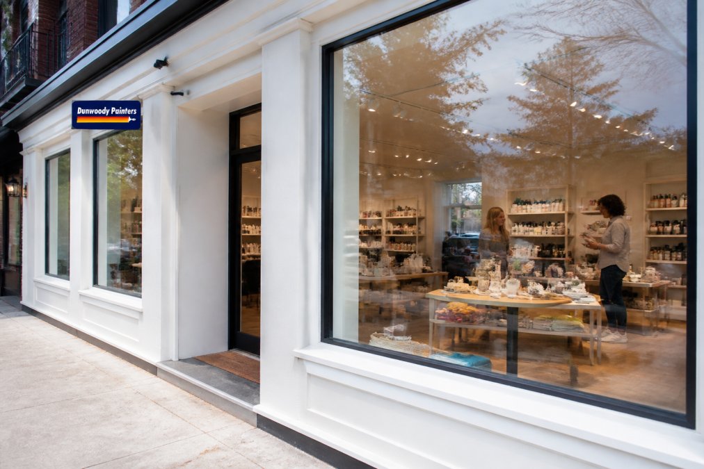 Freshly painted retail storefront with bright, clean walls and professional finishes, customers visible shopping inside, natural daylight streaming through large windows