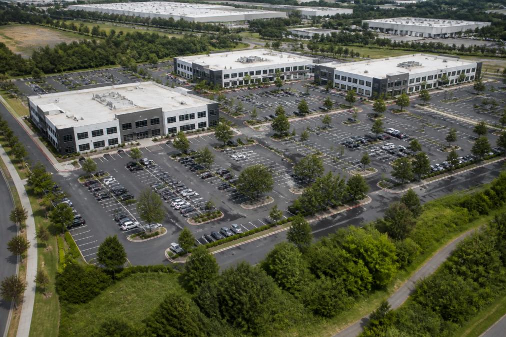 Aerial view of a commercial property complex with multiple buildings, parking lots, and landscaping captured from above, showing the perspective and detail that drone photography provides
