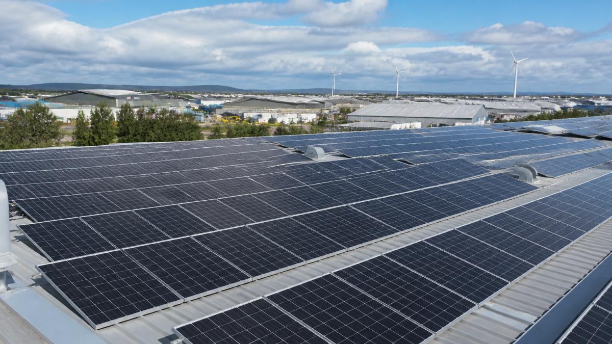 Rows of commercial solar panels on a warehouse roof, providing a high-performance alternative to solar vs wind setups.