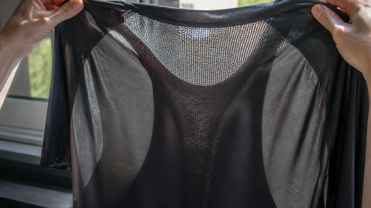 Close-up of a gym top held up to daylight showing mesh ventilation panels and knit structure