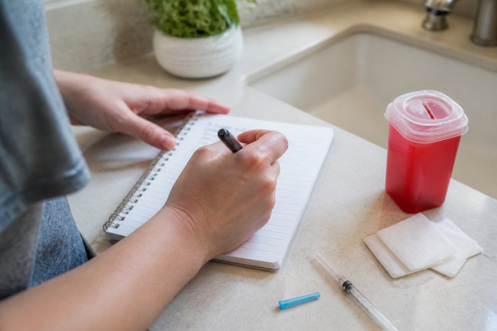 Person using a smartphone app to track rotation sites while self-administering injections at home.