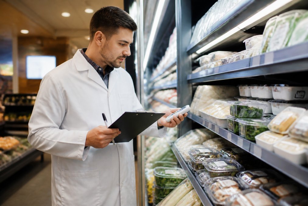 Mitarbeiter führt für die Compliance Lebensmittelindustrie Hygienekontrollen mit Checkliste und Thermometer im Handel durch.