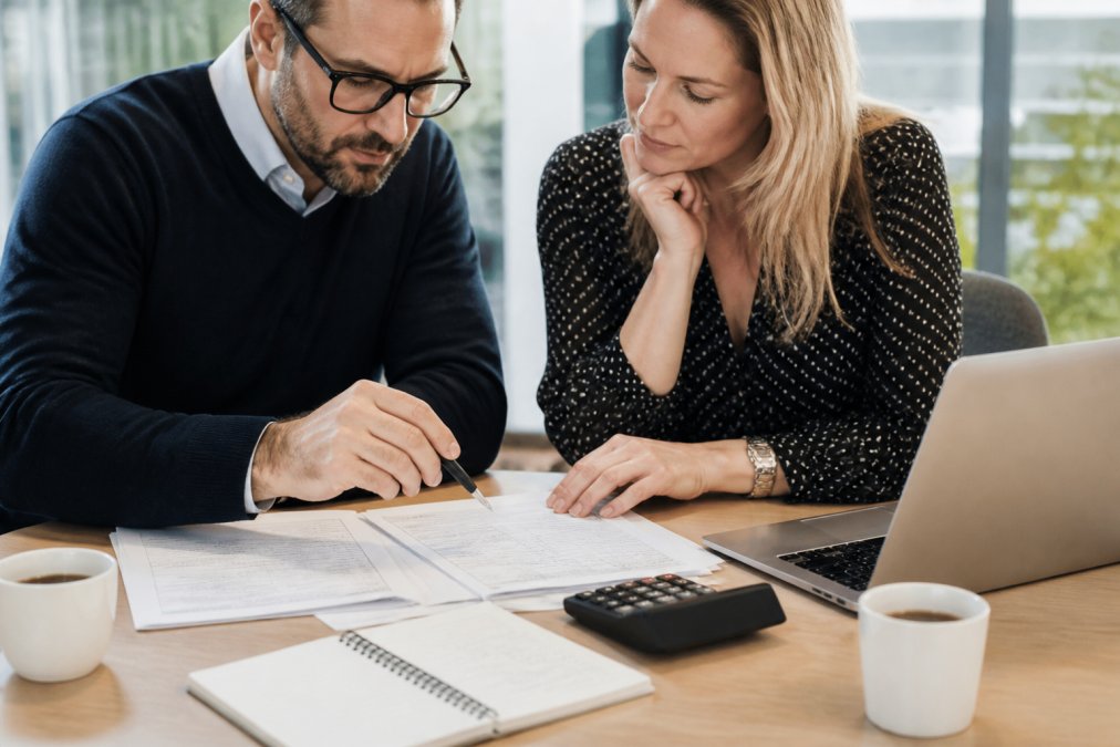 Business owner and broker reviewing documents while consolidating business insurance at a bright office desk