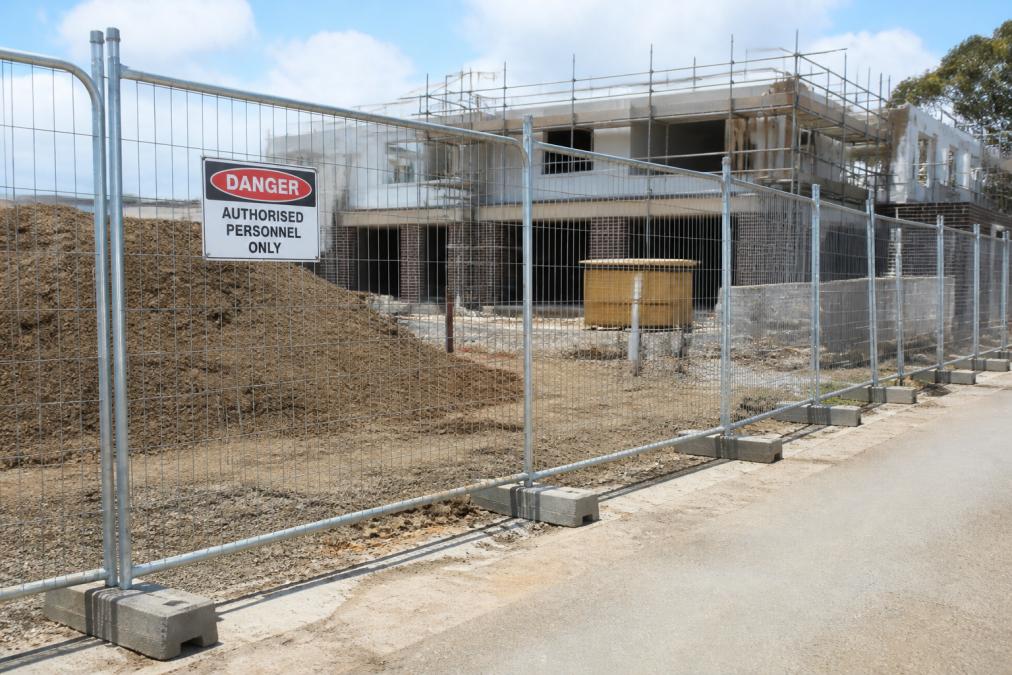 Temporary security fencing installed around a construction site perimeter, showing galvanised steel panels secured with concrete feet and 'Authorised Personnel Only' signage visible in natural daylight