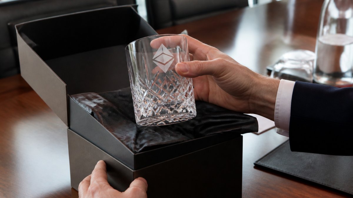 Hands lifting an etched crystal glass from premium packaging, illustrating corporate gift trends and unboxing processes.