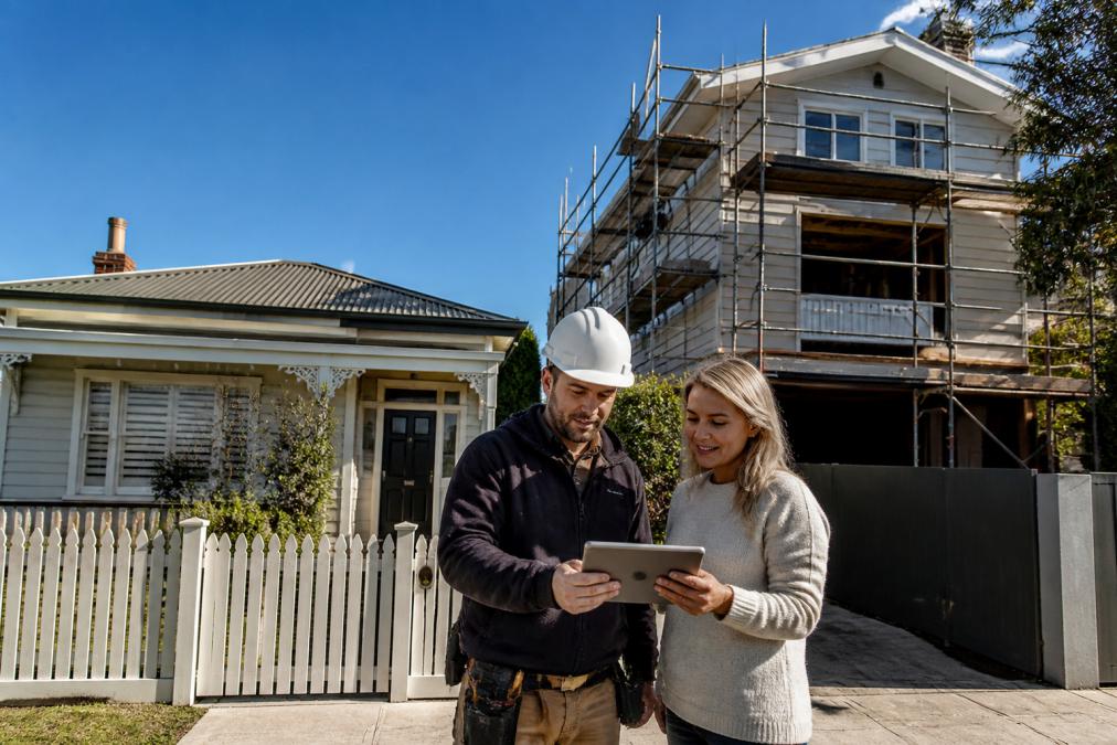 Builder and homeowner reviewing plans for home extensions Melbourne during a second-storey build