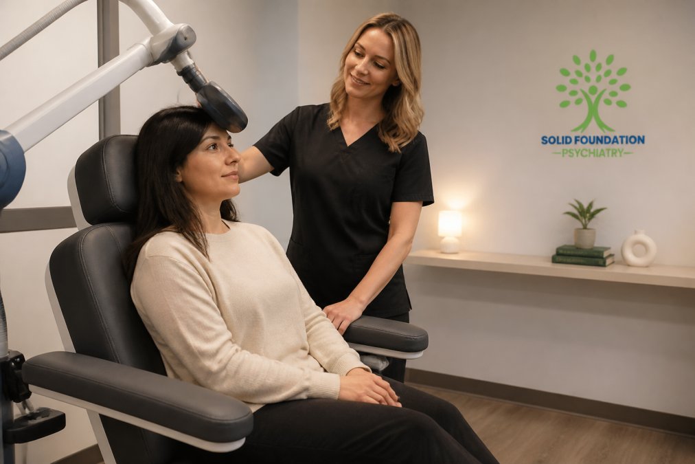 Calm clinical setting with patient seated in comfortable treatment chair, TMS magnetic coil positioned near head, supportive clinician nearby monitoring treatment in modern therapy room with soft lighting