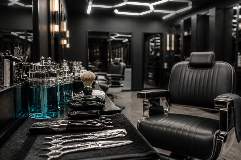 Espace de barbier propre et luxueux avec chaises confortables, outils désinfectés visibles, et éclairage professionnel hexagonal, montrant l'attention aux détails et à l'hygiène