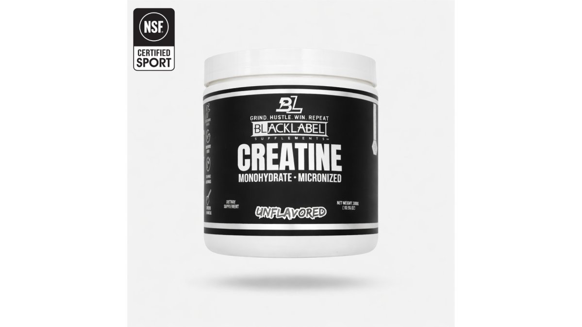 A clear scoop of white creatine monohydrate powder being poured into a glass of water on a gym bench, with a shaker bottle and gym bag blurred in the background