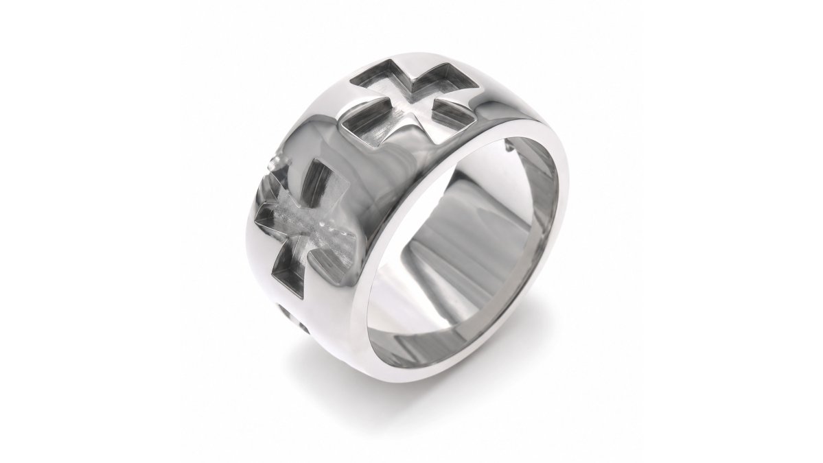 Man's hand wearing polished stainless steel cross cutout band ring with multiple crosses cut through the band, photographed in natural daylight to show the sharp detail and light passing through the openwork