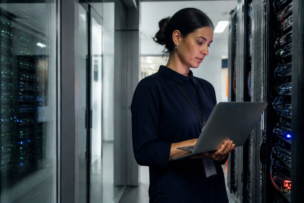 Security architect monitoring cryptographic authorization logs and agent execution metrics on multiple high-resolution displays in a modern enterprise security operations center, with network diagrams and real-time agent activity dashboards visible