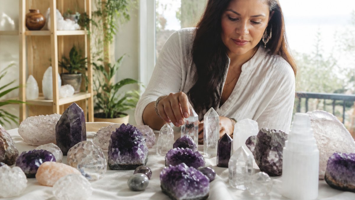 Raw and polished quartz, amethyst, and selenite crystals glowing in natural sunlight on white linen fabric
