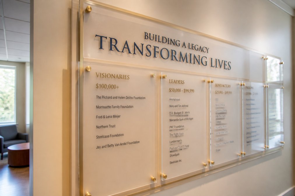 Close-up of a custom acrylic donor wall display with illuminated text and donor names, showing clear typography and visual hierarchy in an institutional hallway