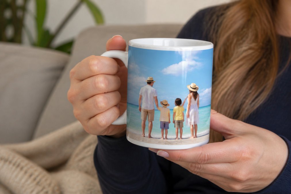 Hands holding a custom ceramic mug with a vibrant full-color photo print of a family or travel scene, showing detail of the glossy finish and rich color saturation under natural lighting