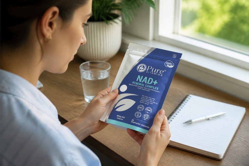 Person reading supplement label closely in natural light, examining ingredient list and dosage information on a bottle