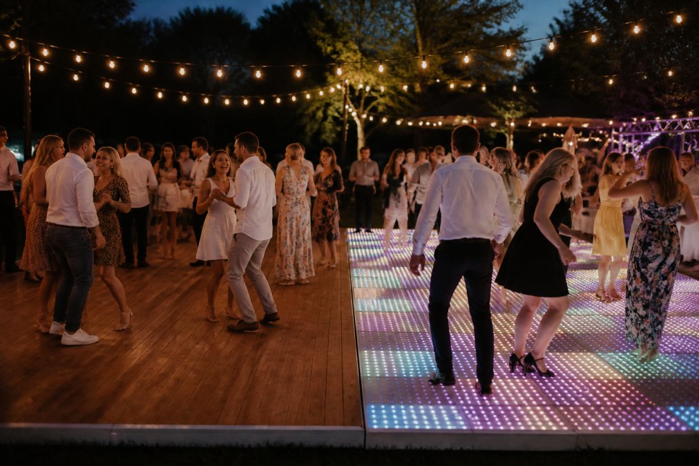 Twee verschillende dansvloertypen naast elkaar: LED-vloer met kleurrijke effecten en houten vloer, beide met mensen die erop dansen, contrast zichtbaar
