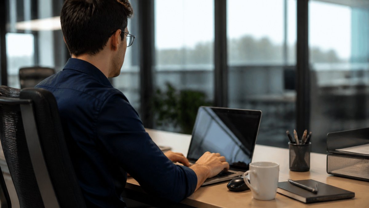 Profesional trabajando en oficina moderna frente a múltiples pantallas mostrando dashboards con gráficos, datos en tiempo real y análisis de información