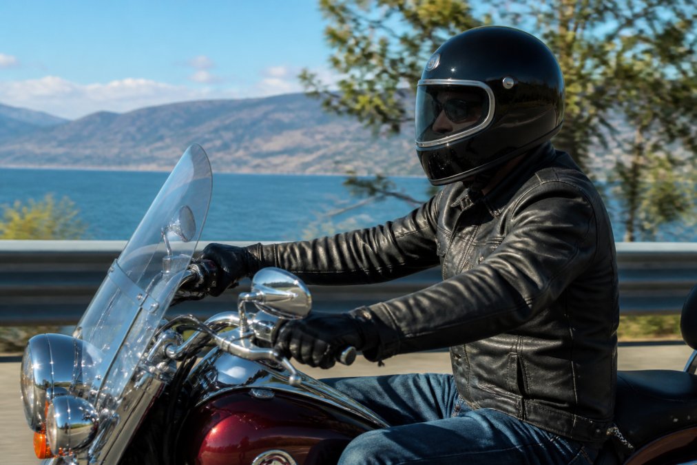 Rider wearing Daytona full-face helmet on cruiser motorcycle in daylight, showing retro styling and overall fit in riding position
