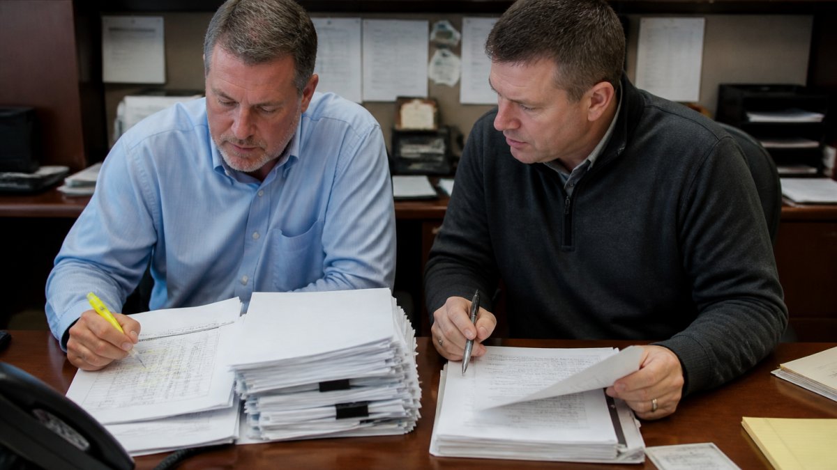 Controller and consultant reviewing invoices to streamline dealership expense management processes