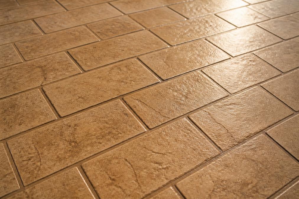 Close-up of finished stamped concrete surface showing detailed brick-pattern texture with warm integral color and natural light reflecting off the sealed surface
