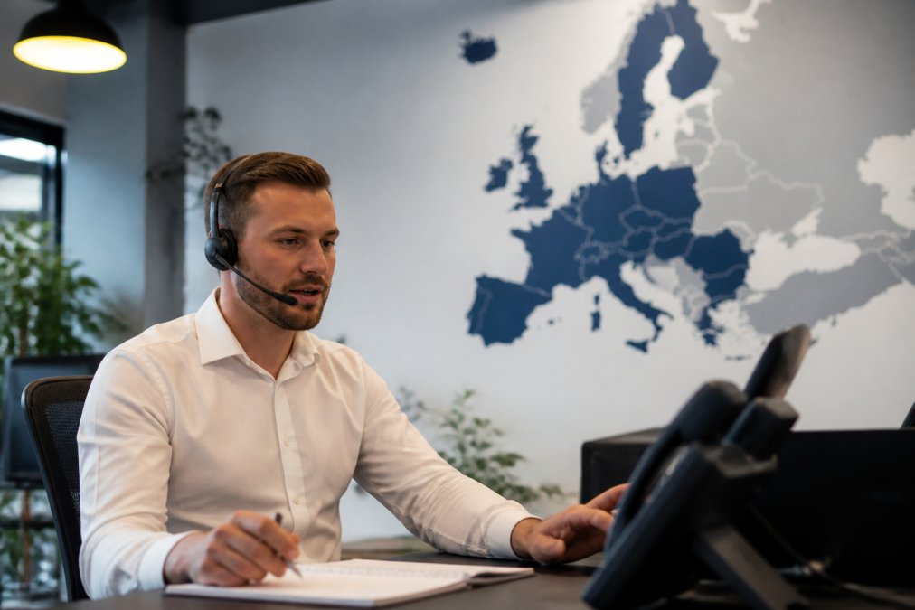 Sales professional using a headset and data monitors at a demand generation agency office