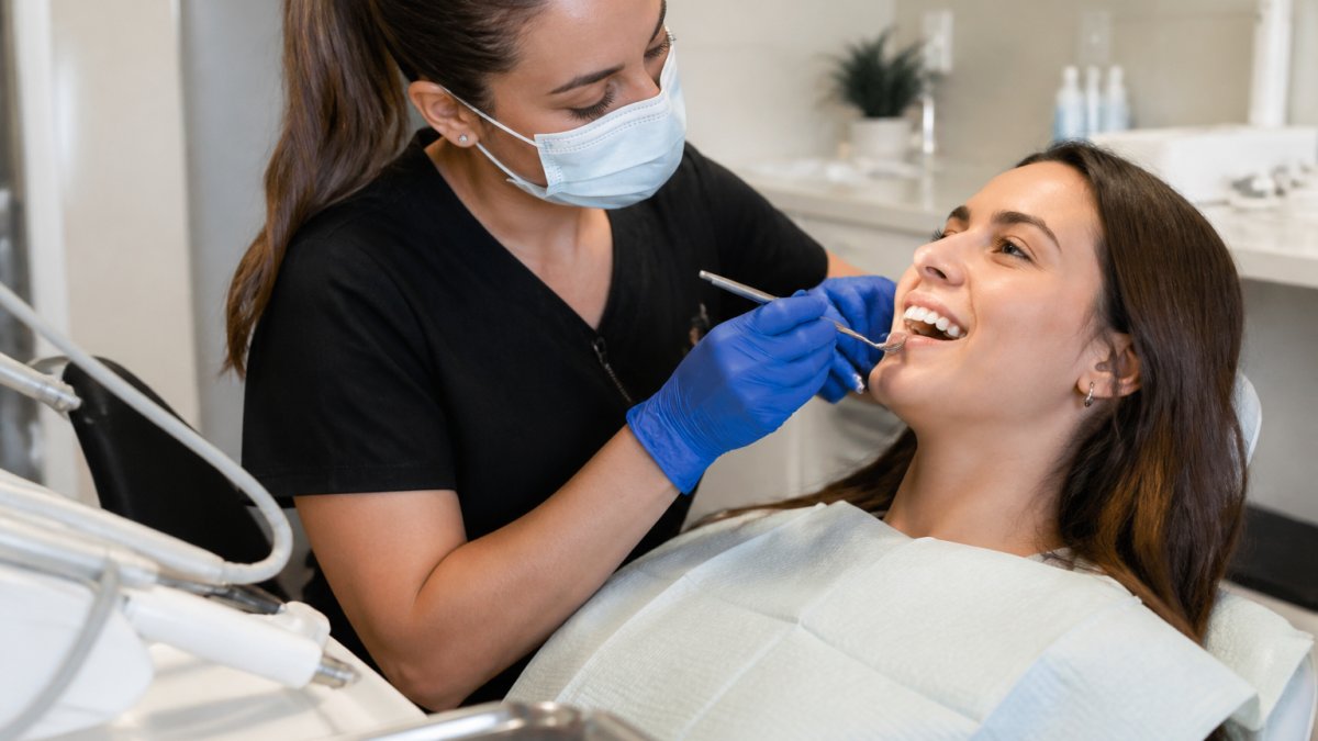 A dental hygienist in gloves gently examining a relaxed patient's teeth in a bright, modern dental office, with a calm and reassuring atmosphere