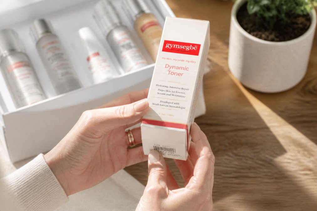 Close-up of hands holding a skincare product box while checking packaging for authenticity markers and batch numbers in natural daylight