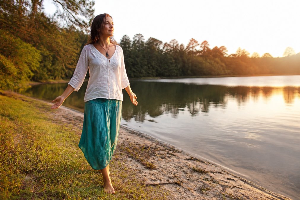 Develop Psychic Awareness: Strengthen Your Intuition 2 Person walking barefoot on grass or sand with hands open in a natural outdoor environment, trees or water visible in the background, soft natural lighting