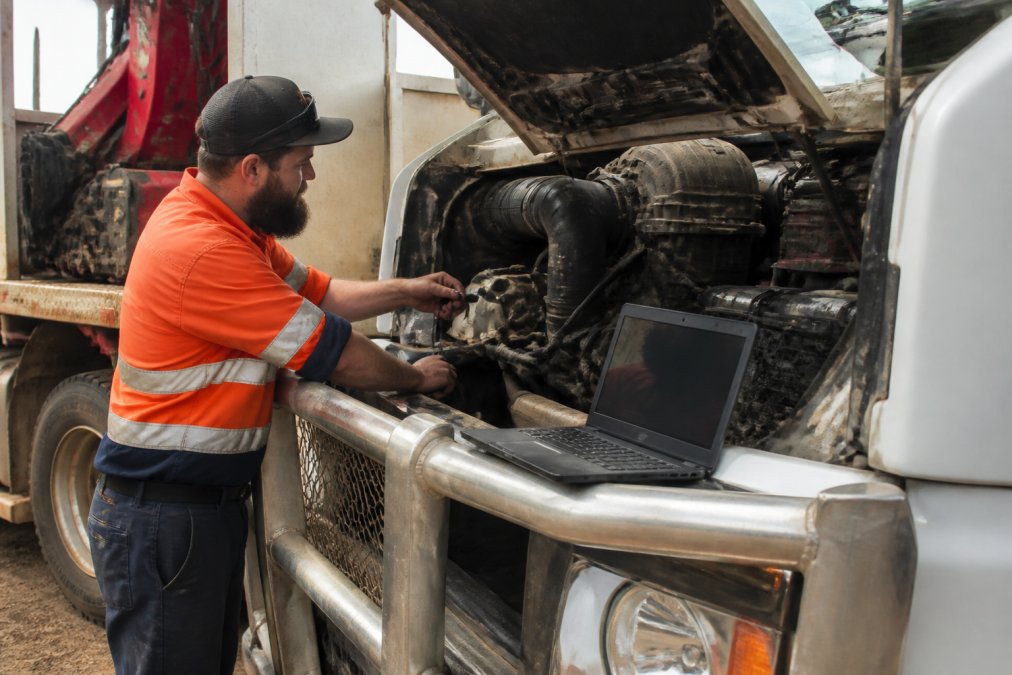 Technician connecting a scan tool to a truck for diesel engine diagnostics and live data analysis process