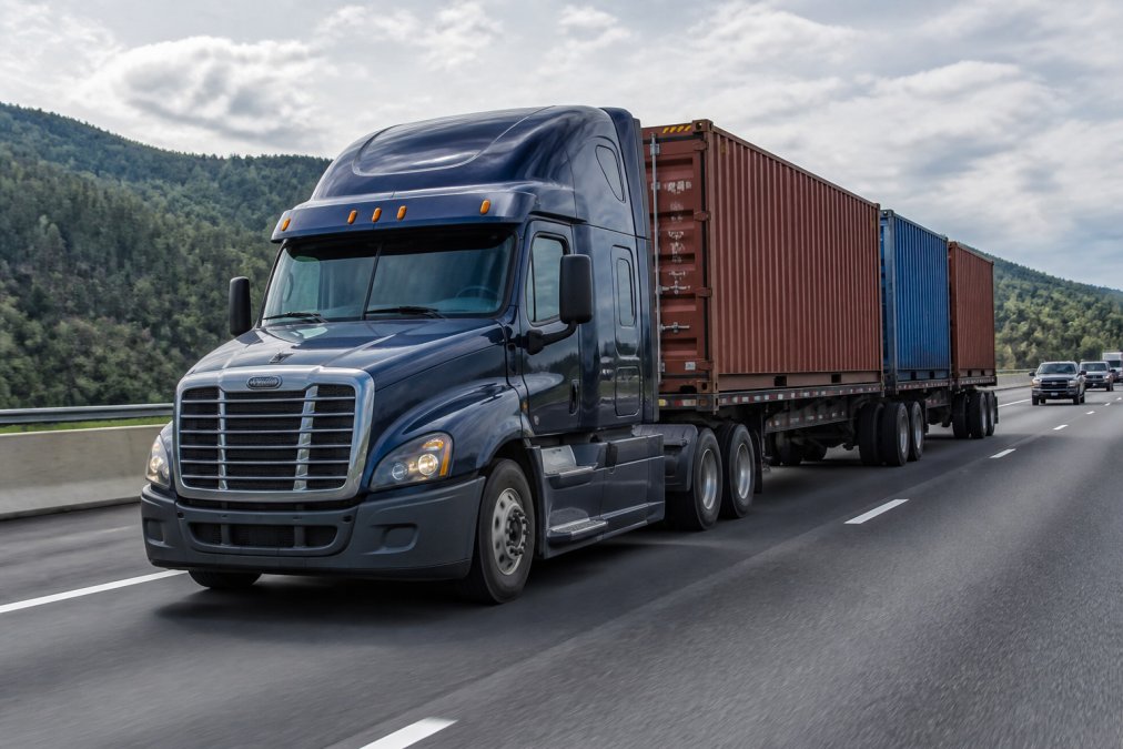 Professional heavy-duty diesel truck fully loaded with cargo containers on a multi-lane highway, demonstrating payload capacity and sustained hauling power under full load