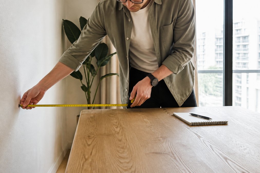 Diagram showing how to measure clearance between dining tables and walls for optimal room spacing.