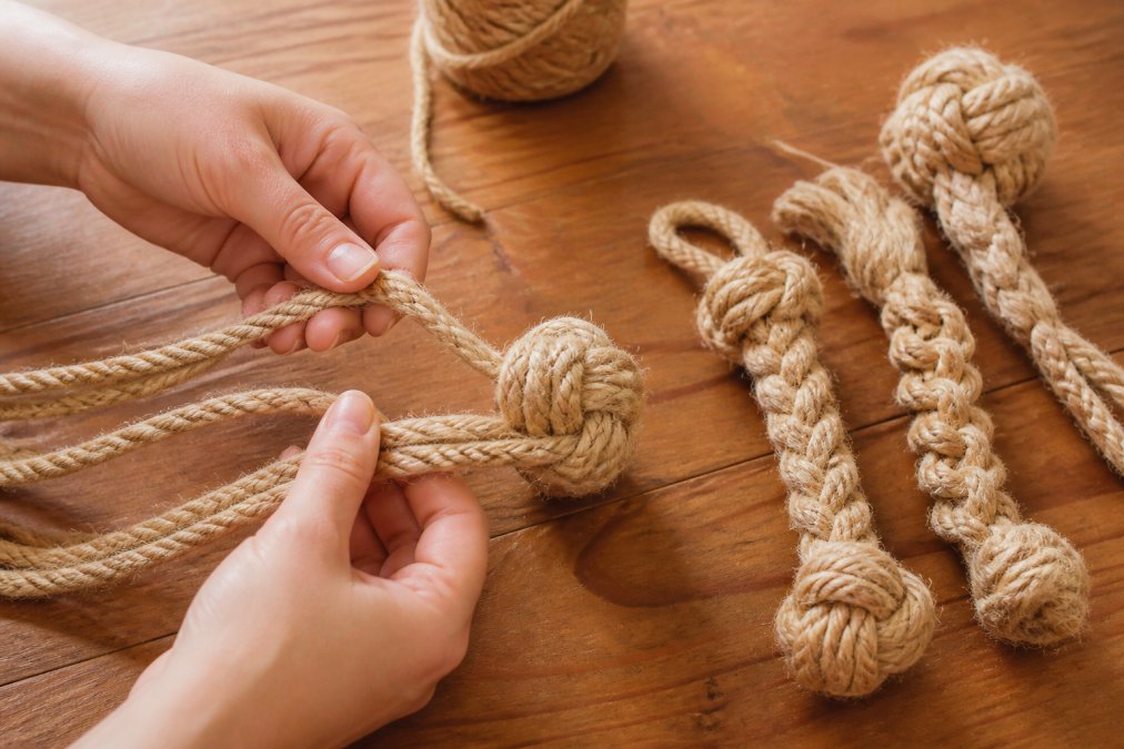 Step-by-step tutorial on braiding jute rope to create DIY enrichment toys for power chewers on a wooden surface.