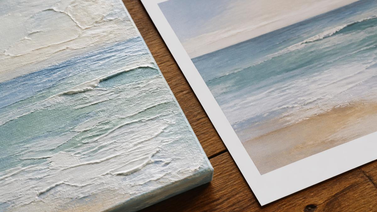 Close-up of an original textured acrylic painting with visible raised brushstrokes and layered paint sitting beside a high-quality fine art print on matte paper, showing the subtle differences in surface texture and dimensional depth under natural side lighting