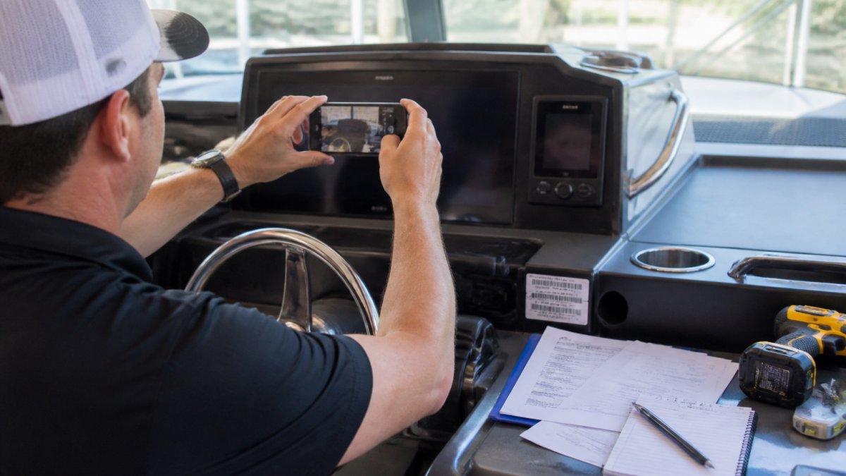 Boat owner photographing a chartplotter screen and serial number label to document a marine electronics claim