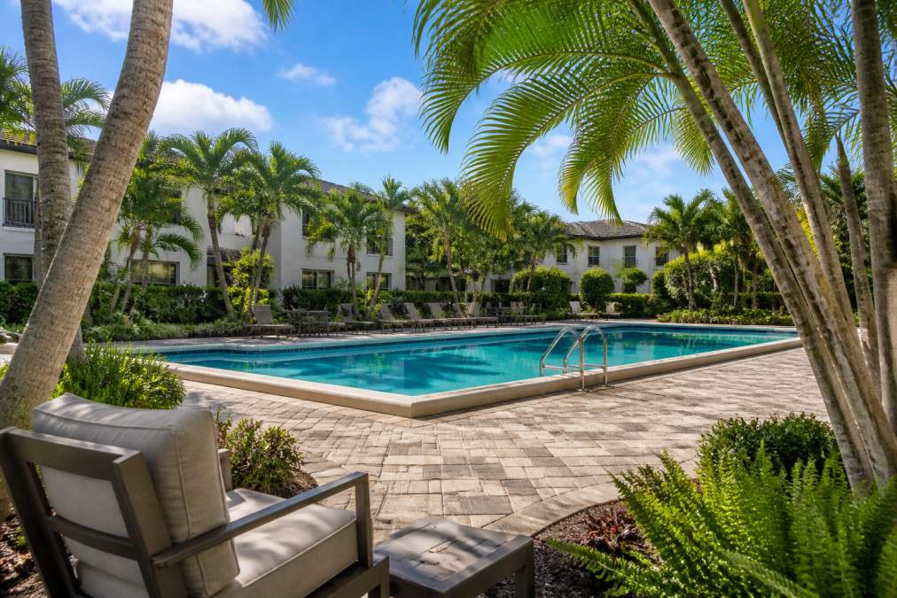 Does Travis Kelce Have a House in Boca Raton? 2 Modern garden-style apartment community in Boca Raton featuring resort-style pool surrounded by lush tropical landscaping, comfortable seating areas, and serene residential architecture in natural afternoon light