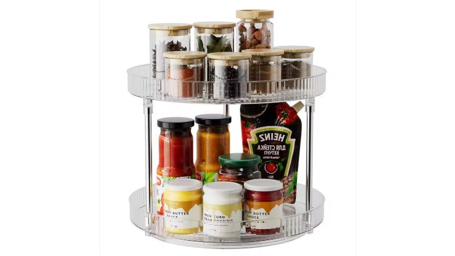 Well-organized kitchen pantry shelf with a double-layer rotating spice rack turntable displaying labeled glass jars, alongside neatly stacked clear containers with compartmentalized dry goods, minimal visual clutter, warm kitchen lighting