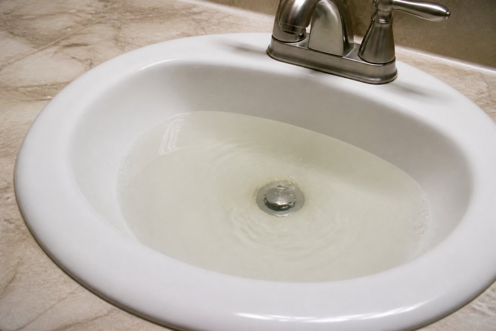 Infographic illustrating slow sink drainage signs to consider before checking drain cleaning service pricing.