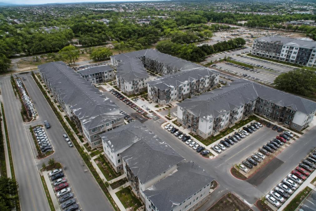 Aerial view of a multi-family residential apartment complex with multiple buildings and a parking lot