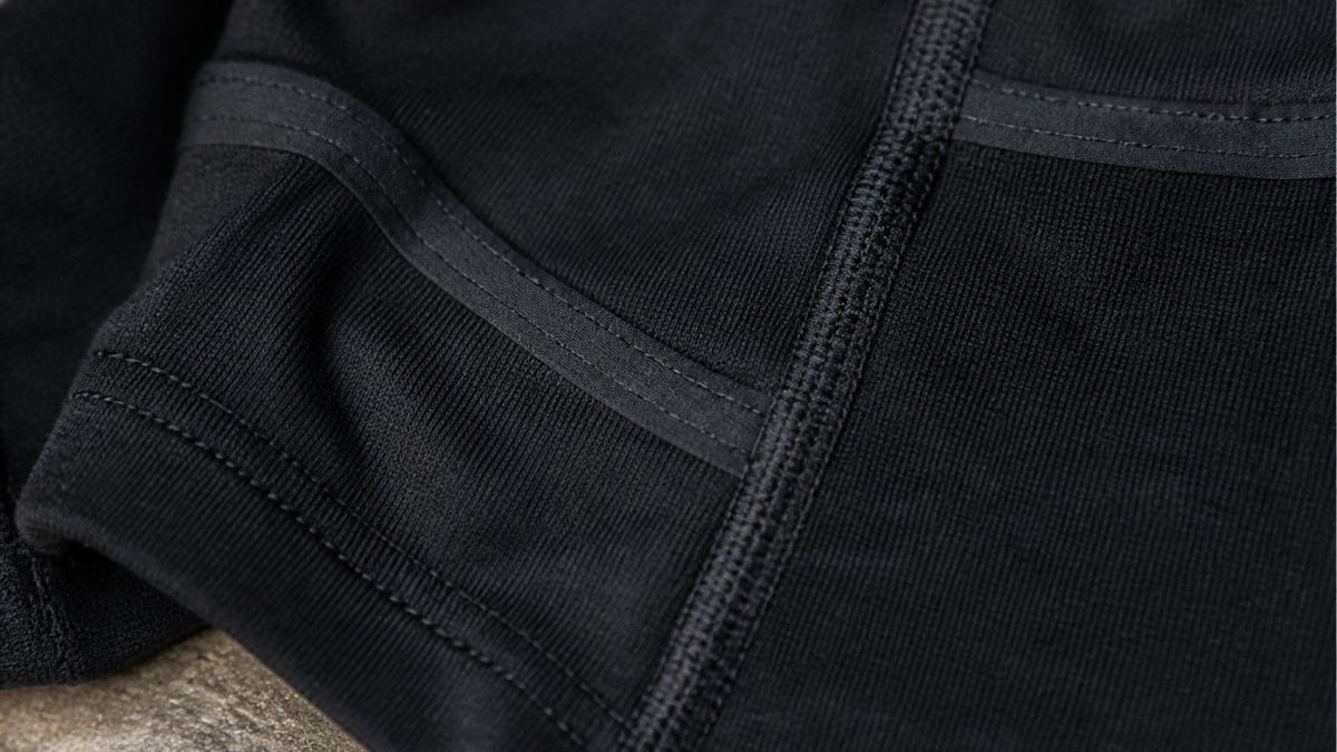 Close-up of heavyweight cotton fabric texture showing reinforced stitching detail and taped seams on a durable rash guard