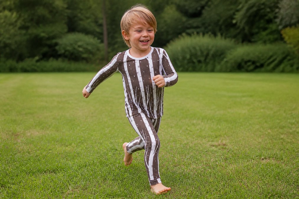 Active child playing outdoors wearing soft bamboo clothing, running through grass with visible movement and comfort, natural daylight
