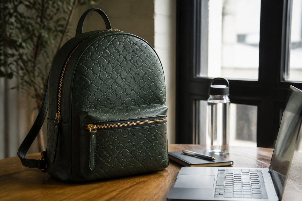 Infographic showing durability features of a dark green everyday carry backpack alongside essential gear items.