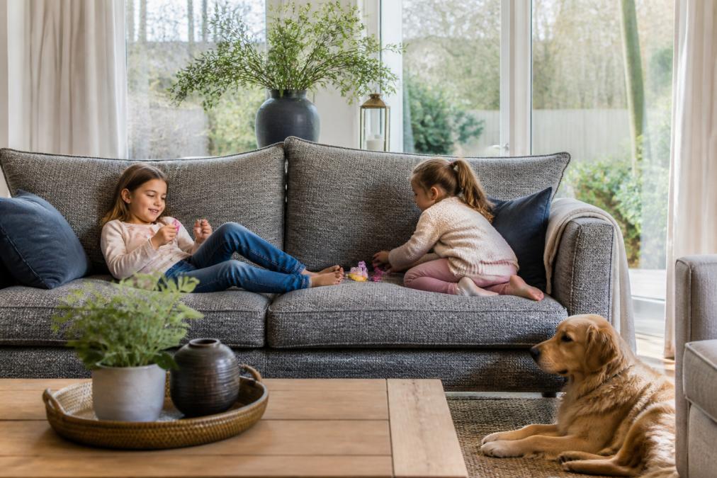 Family living room with children playing on a durable textured sofa, a dog resting nearby, natural daylight streaming through large windows, showing real-world wear resistance in action
