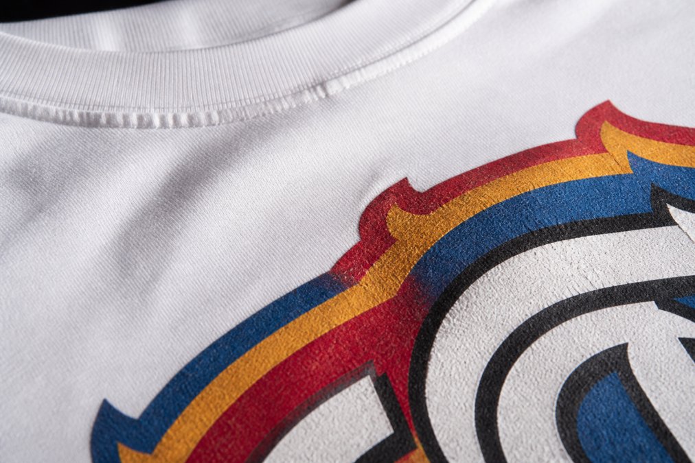 Close-up of a high-quality screen-printed graphic tee showing crisp detail and vibrant colors with visible stitch lines and print texture on white cotton