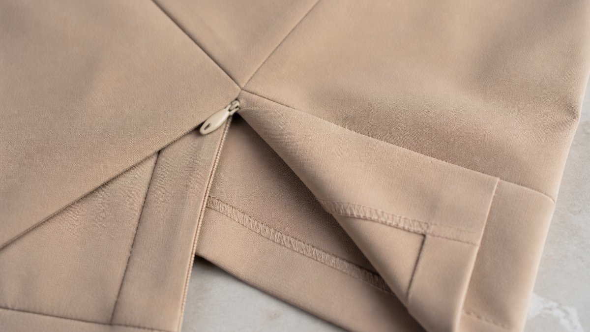 Close-up of expertly finished seams with even stitching, invisible zipper installation, and precision-tailored hem details on premium fabric showing refined craftsmanship
