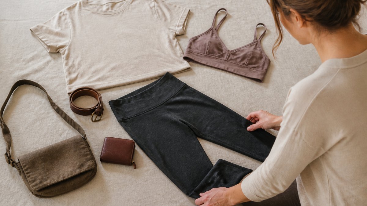 Flat lay of hemp clothing pieces including a t-shirt, leggings, and accessories arranged on a linen background.