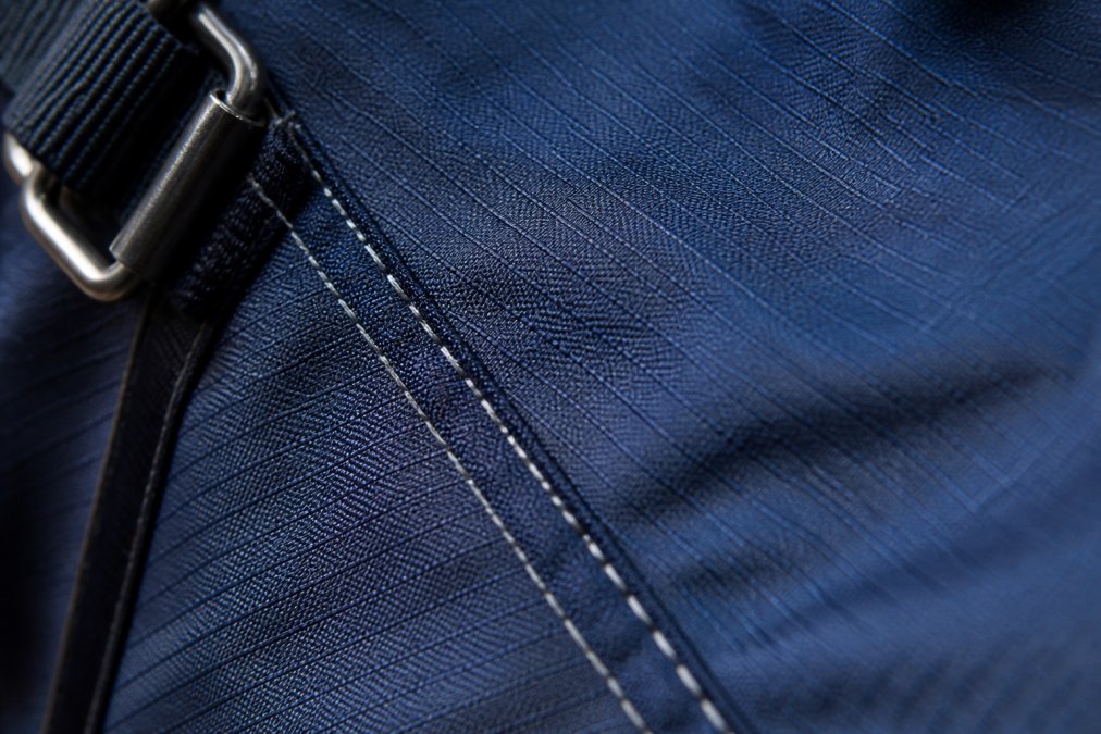Close-up of ripstop fabric texture showing reinforced weave pattern with visible stitching detail on a durable horse blanket