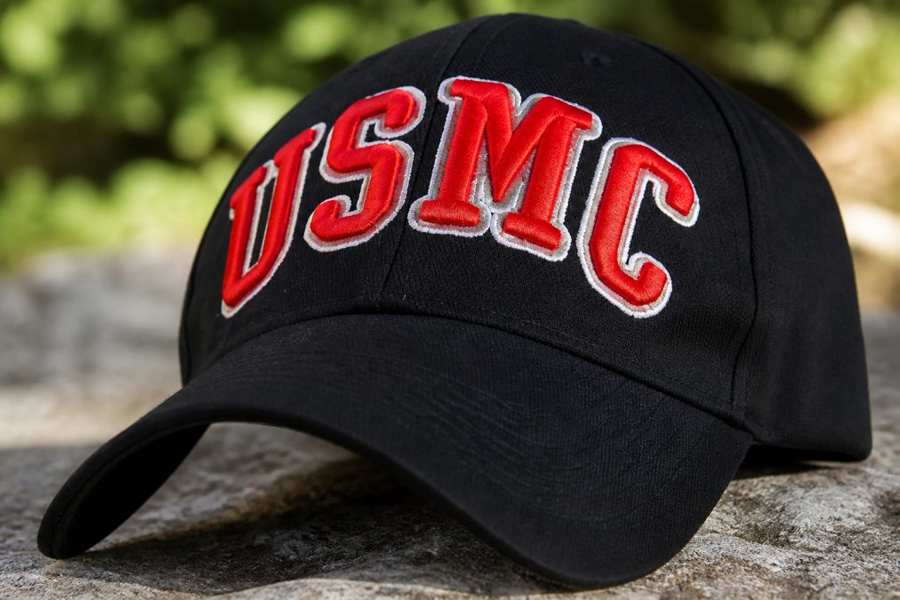 Close-up of high-quality cotton twill fabric with embroidered Marine Corps insignia showing texture, stitching detail, and weave pattern under natural lighting