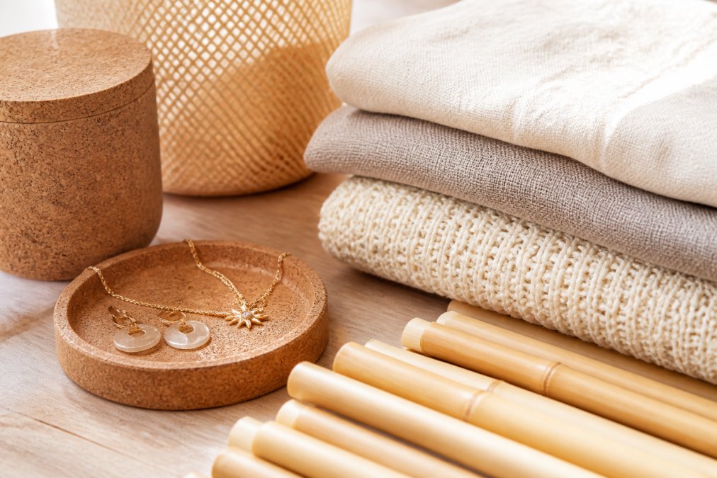 Close-up van natuurlijke materialen zoals kurk, bamboe en biologisch katoen textiel op een licht houten oppervlak met warm natuurlijk licht